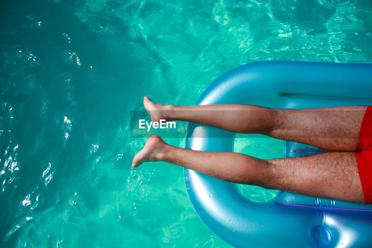 Low section of man relaxing on pool raft