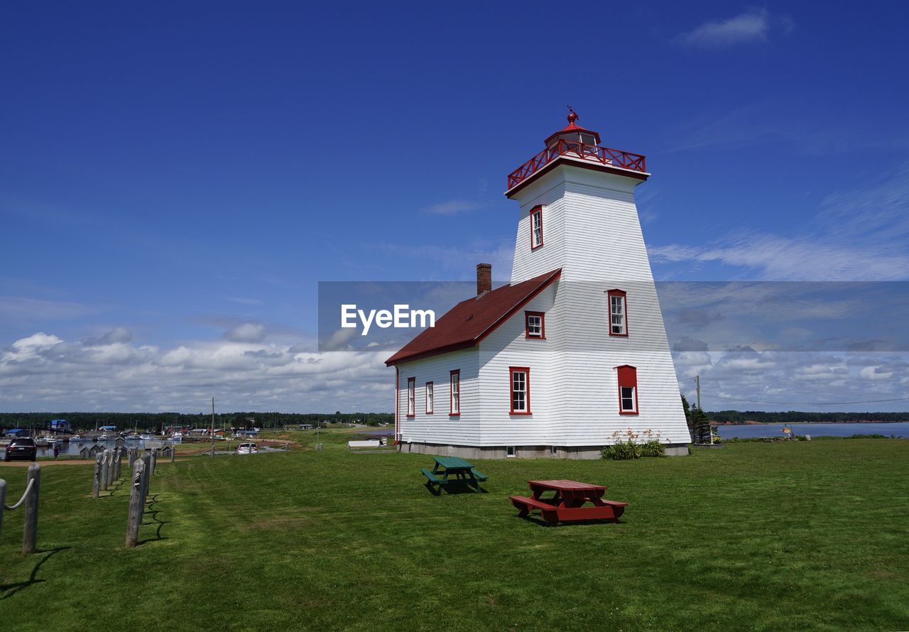 Lighthouse on field against sky