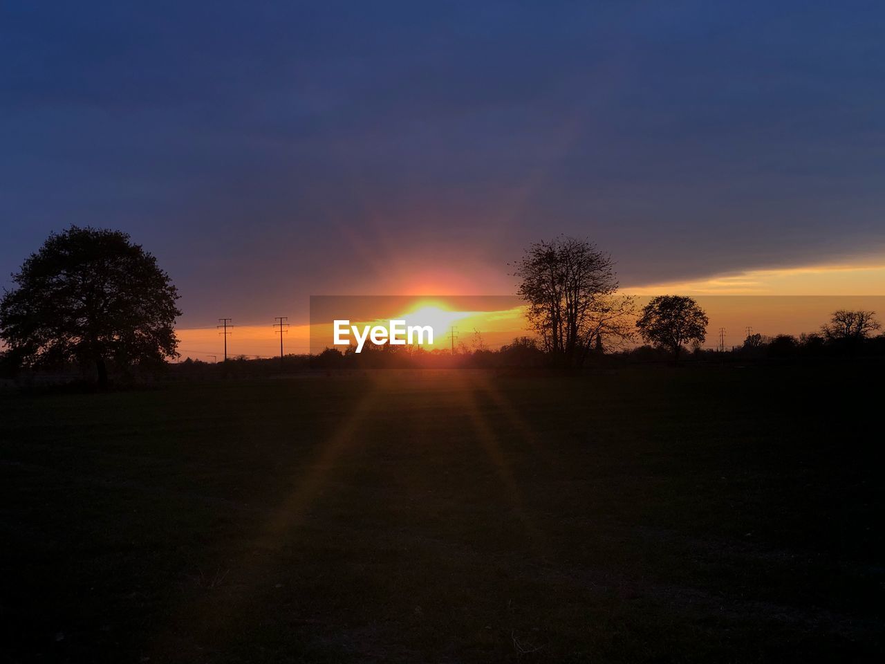 SCENIC VIEW OF SILHOUETTE FIELD AGAINST SKY AT SUNSET