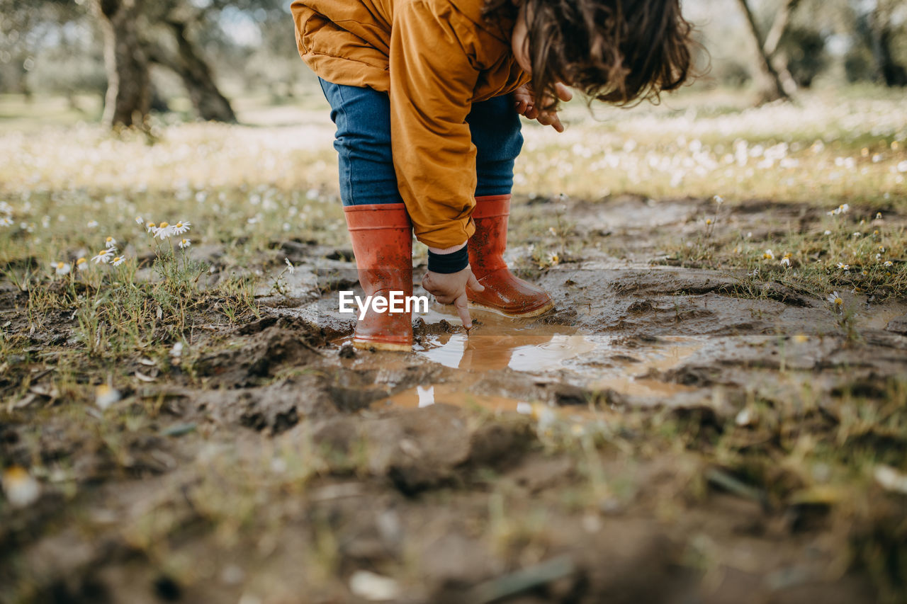 Low section of child standing in mud