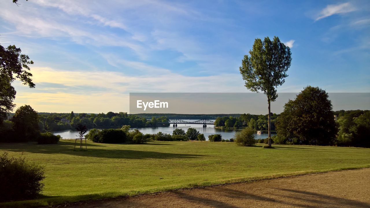 Scenic view of field by lake against sky