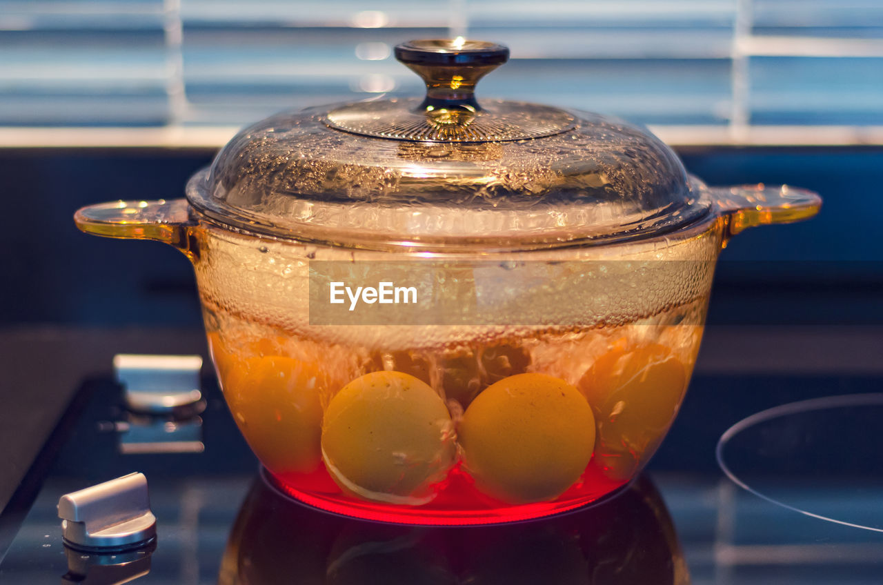 Eggs in boiling water on modern kitchen stove, shallow depth of field