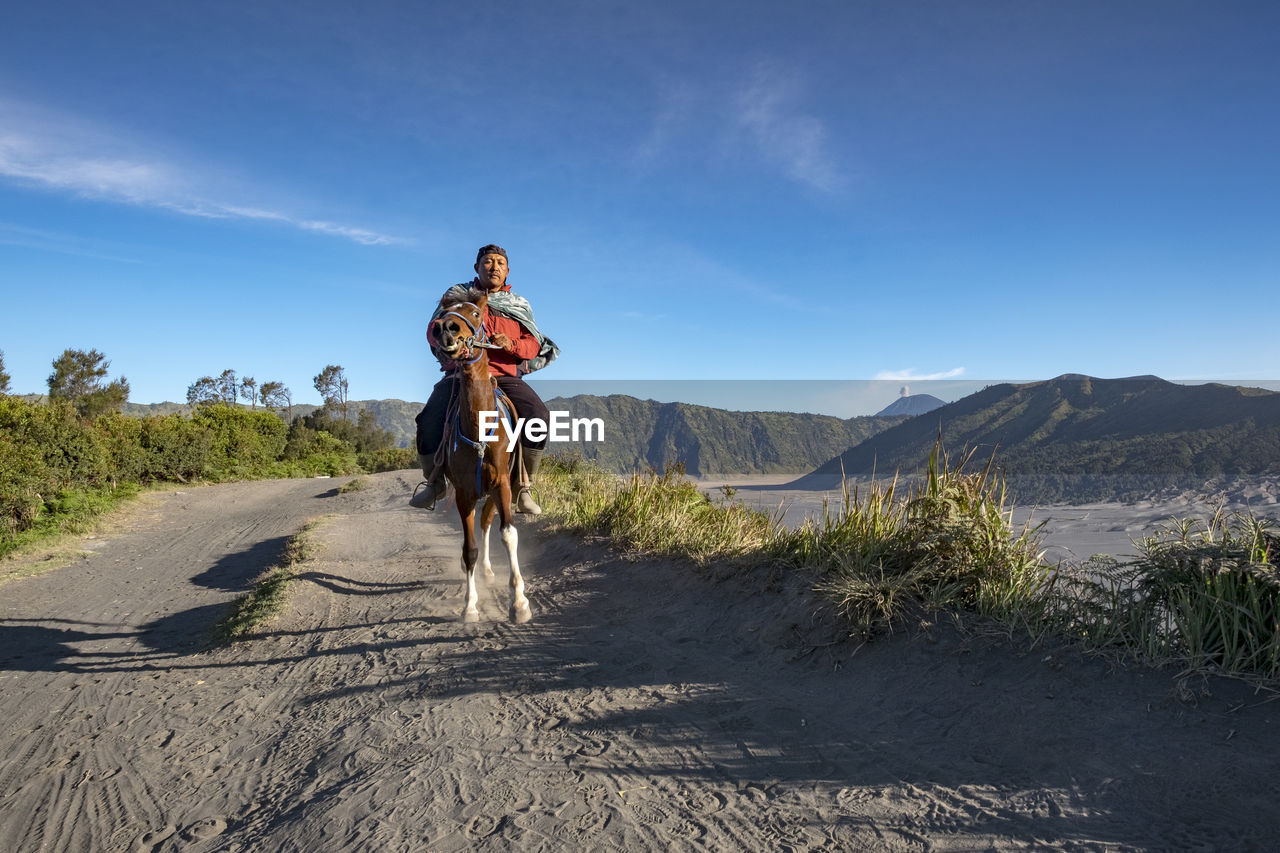 Man horseback riding on sand at desert