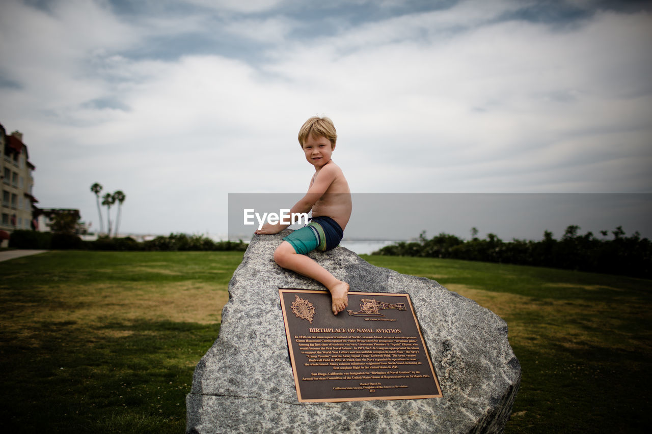 Shirtless six year old boy sitting on rock in coronado