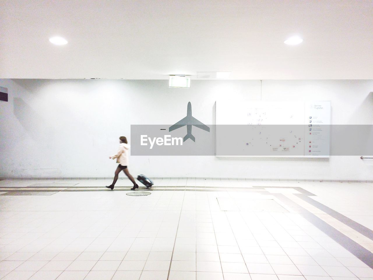 Full length side view of businesswoman with luggage walking in airport terminal