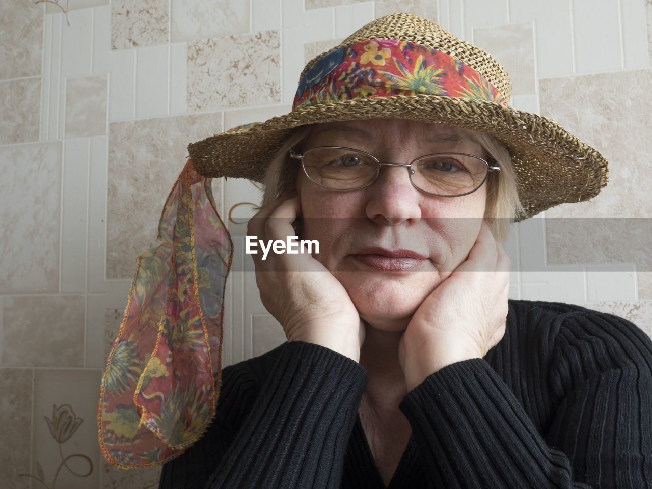 Portrait of woman wearing hat sitting against wall at home