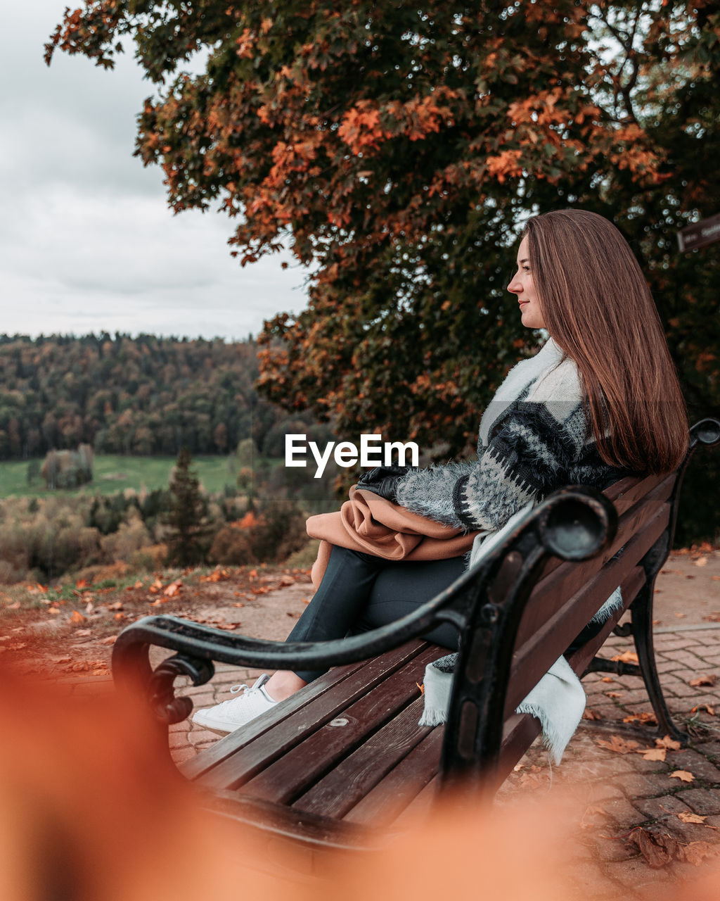 Smiling young woman sitting on bench in park