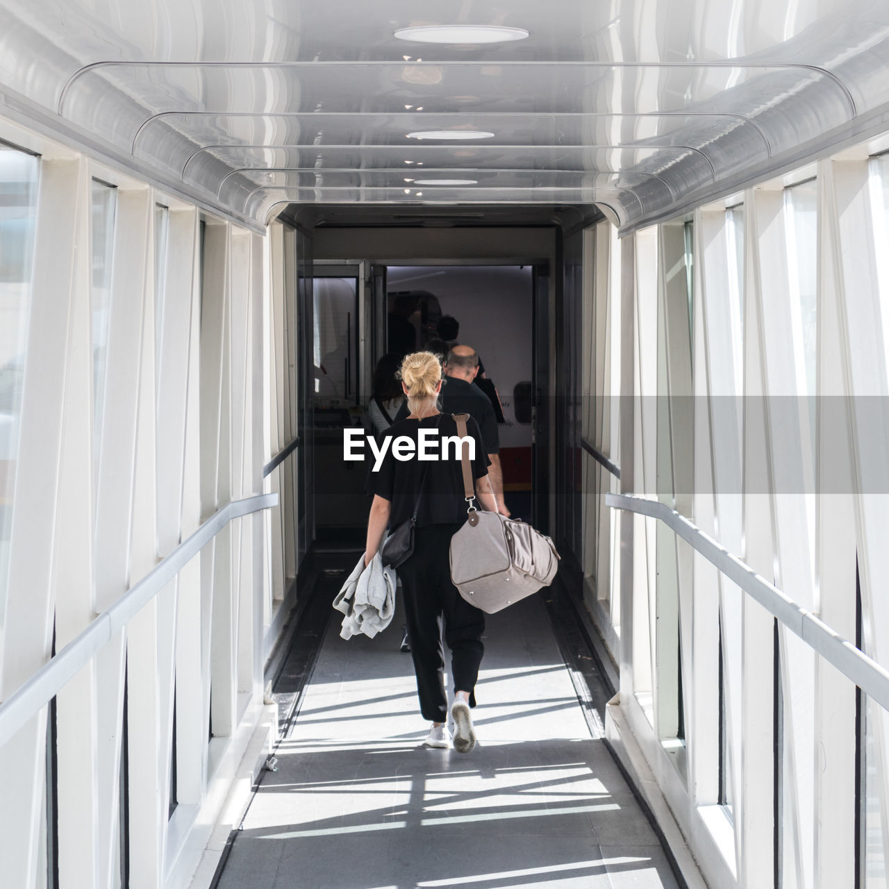 FULL LENGTH OF WOMAN WALKING ON CORRIDOR OF PEOPLE