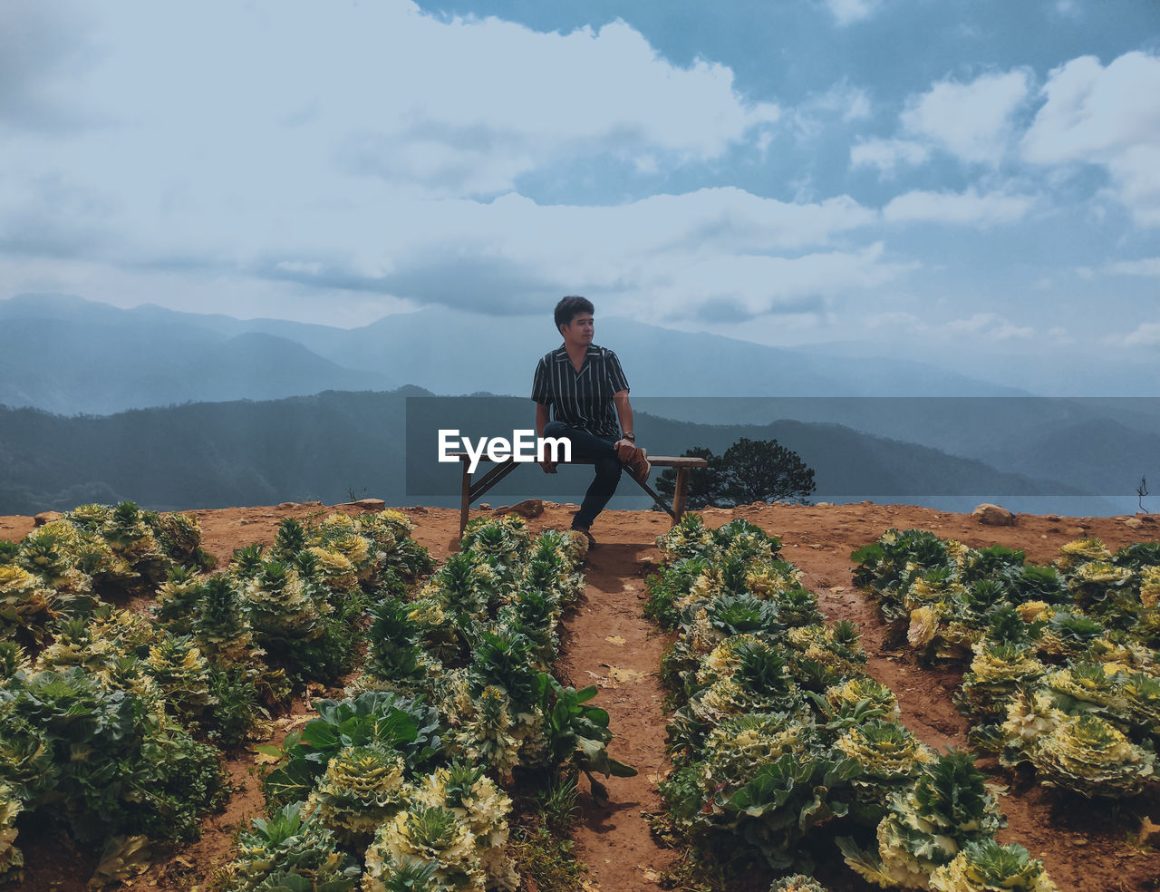 Man sitting by mountain against sky