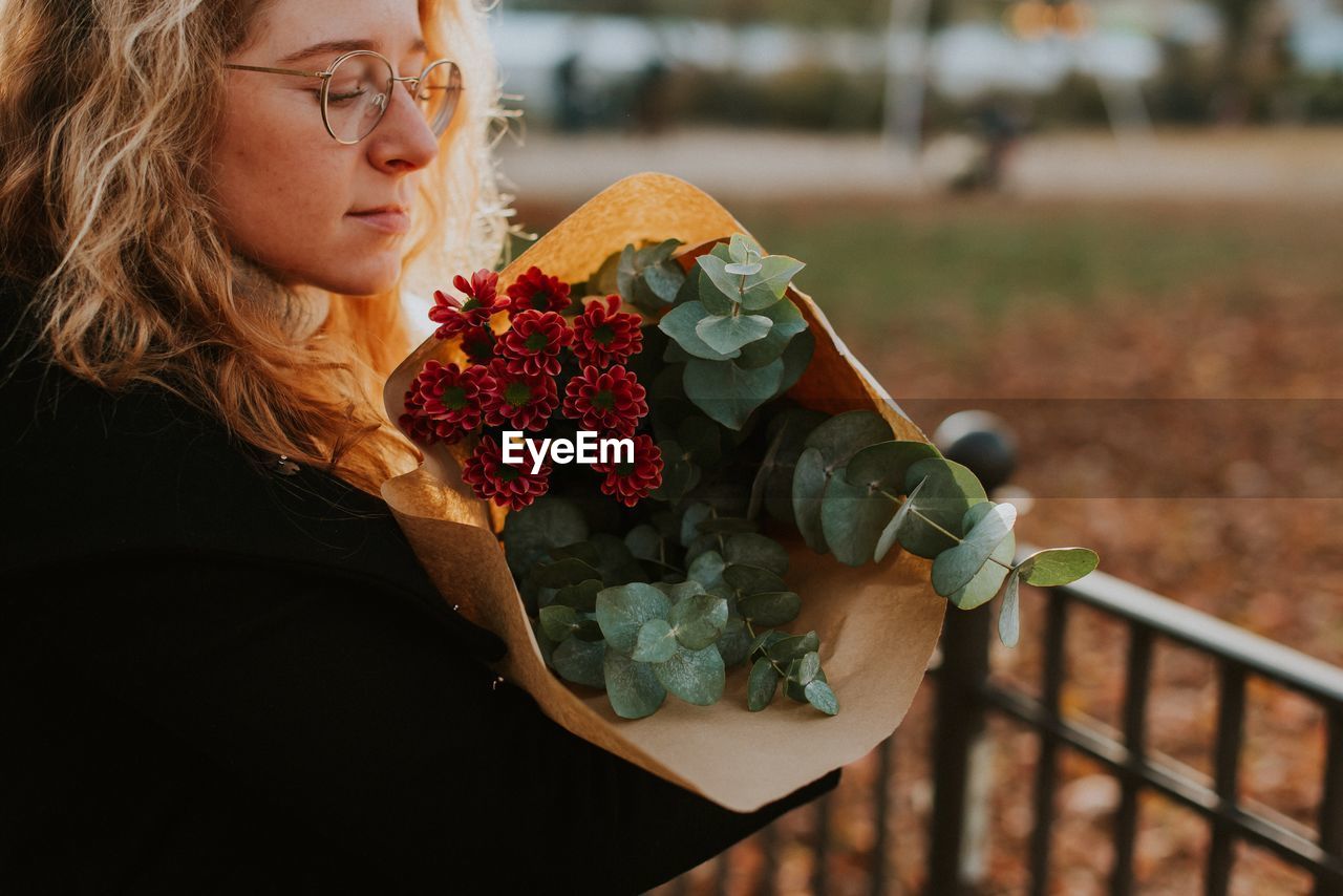 Woman looking at flower bouquet outdoors