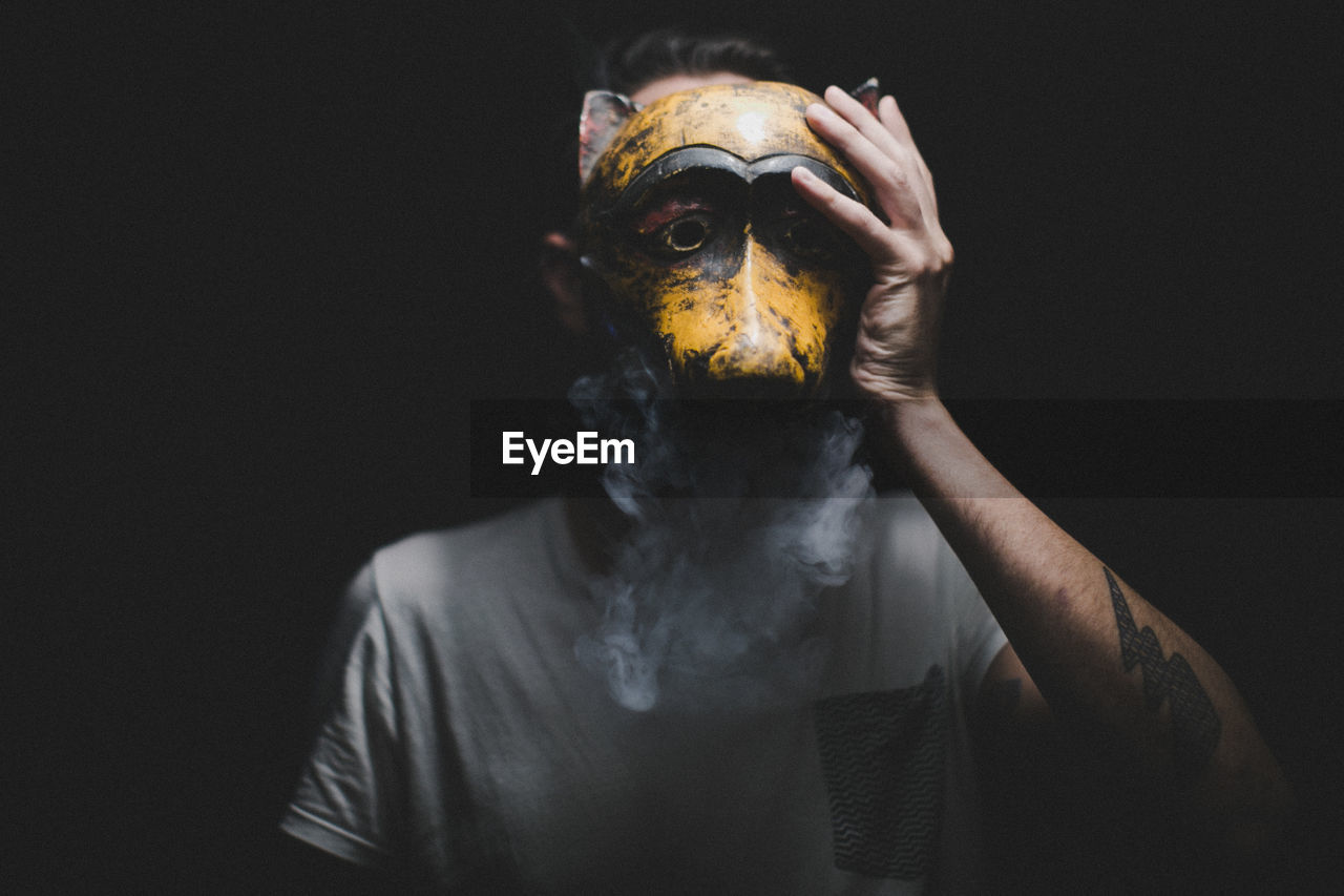 Man wearing mask against black background