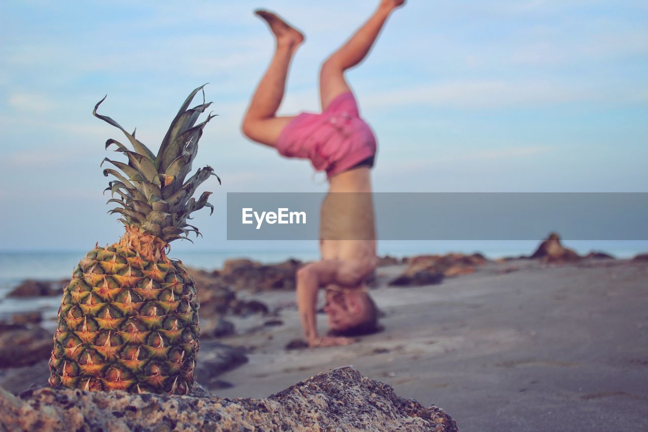 Balancing on head eith pineapple on beach