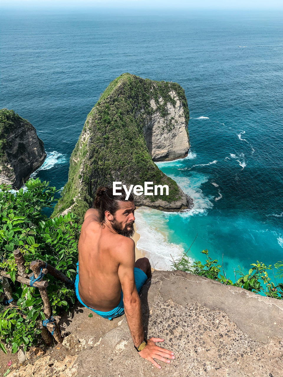 YOUNG MAN ON ROCK AT BEACH