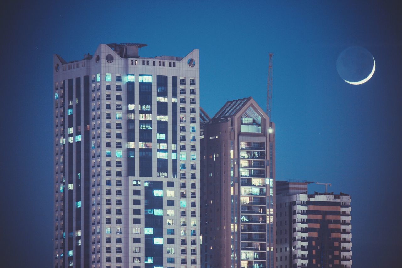 Illuminated buildings against blue sky at dusk