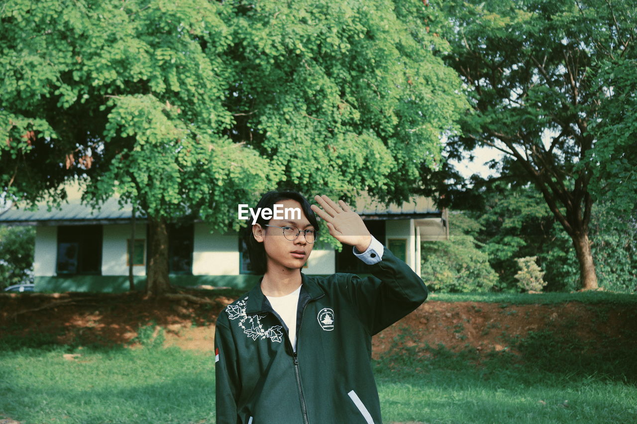 PORTRAIT OF YOUNG MAN STANDING AGAINST TREES