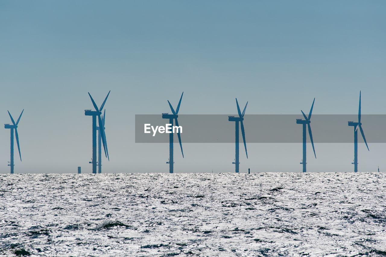 Wind turbines on land against sky