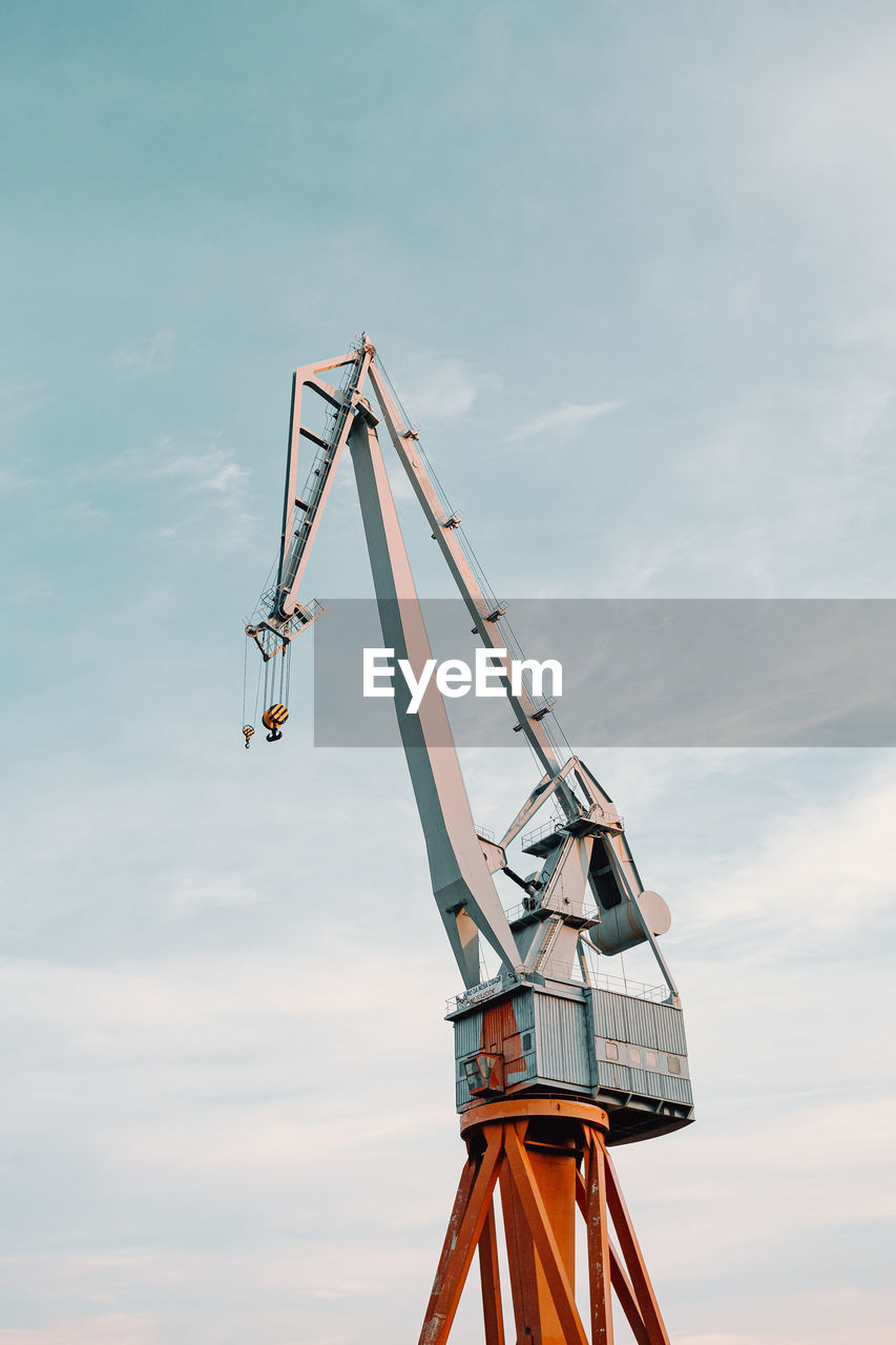 Low angle view of crane against sky