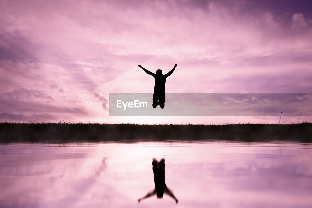 reflection, sky, water, lake, silhouette, morning, cloud, nature, one person, tranquility, sunrise, arm, pink, dusk, beauty in nature, adult, tranquil scene, limb, full length, scenics - nature, arms raised, human limb, leisure activity, lifestyles, vitality, outdoors, idyllic, arms outstretched, horizon, dramatic sky, balance, men, relaxation, landscape, twilight, exercising