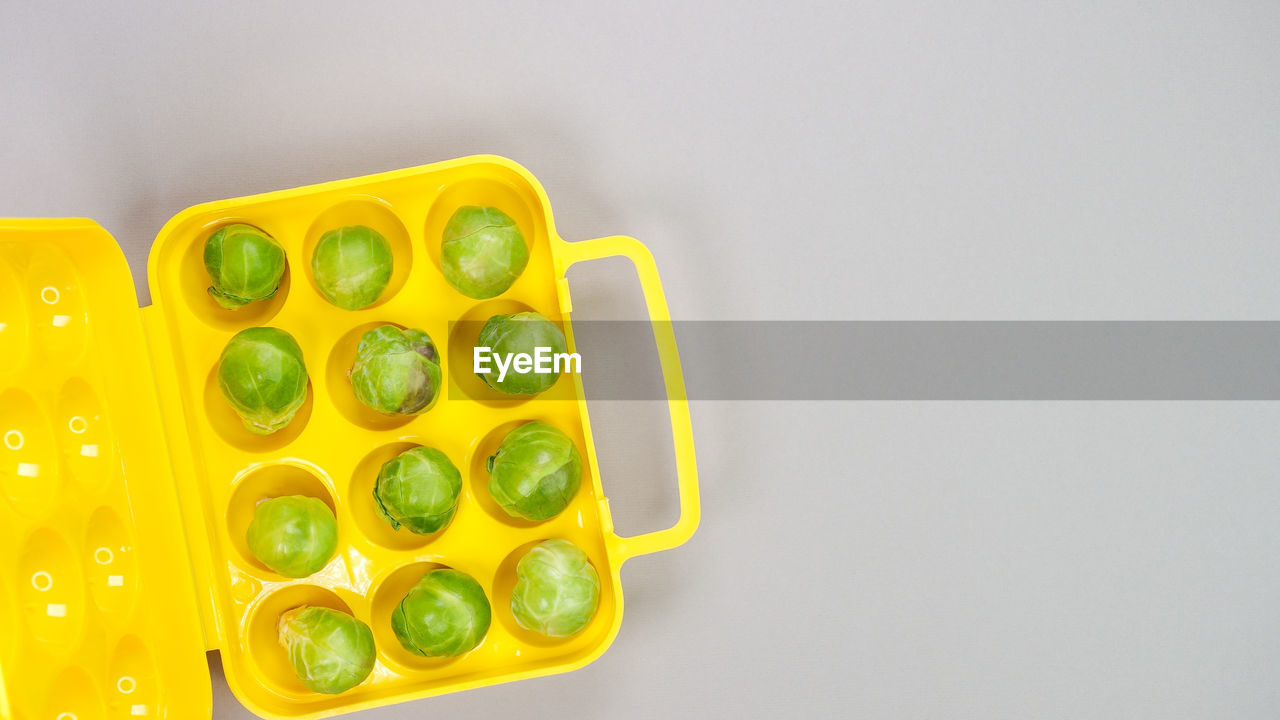 High angle view of raw organic brussel sprouts in yellow pack on grey background