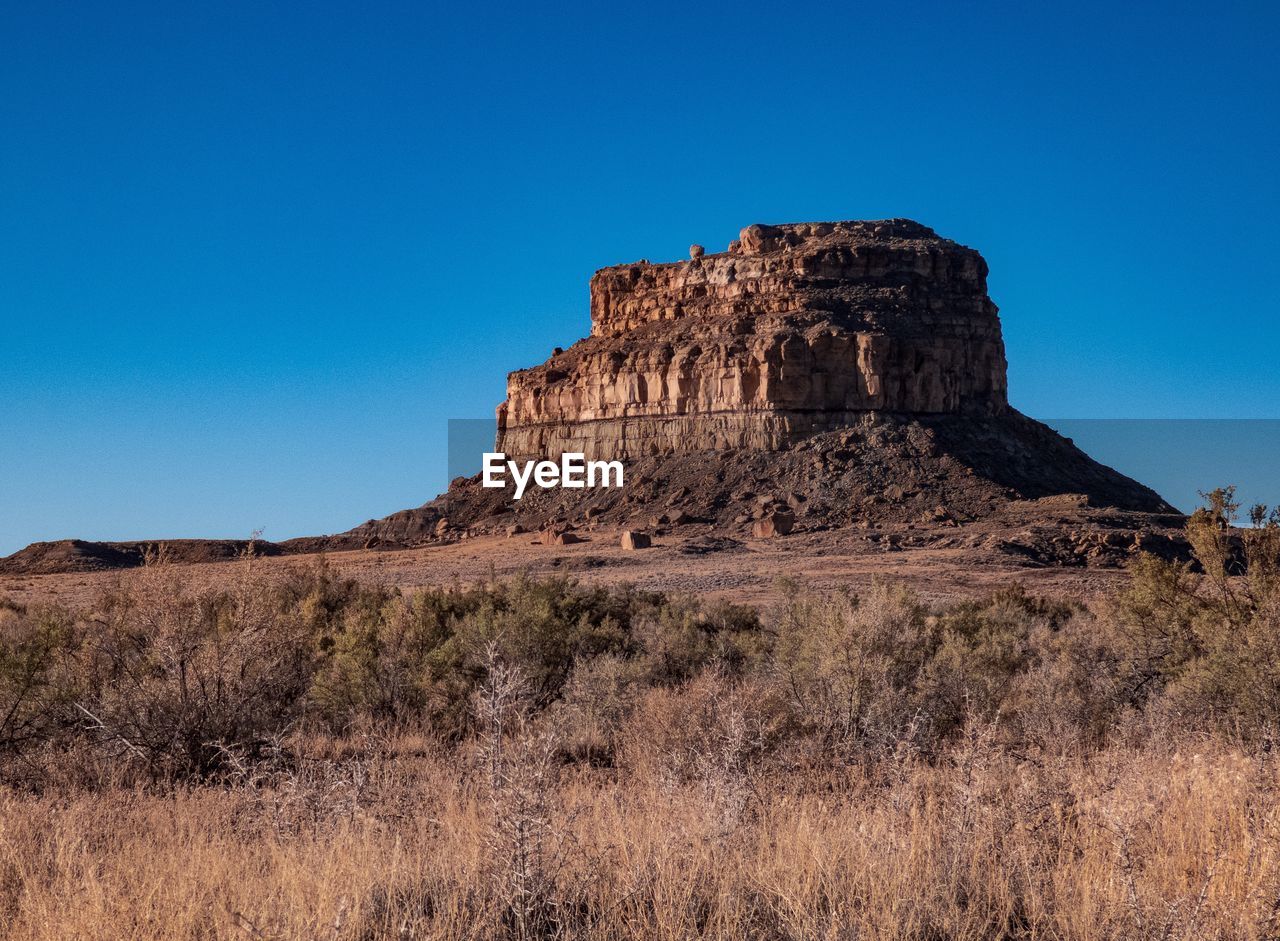 Low angle view of rock formations against clear blue sky