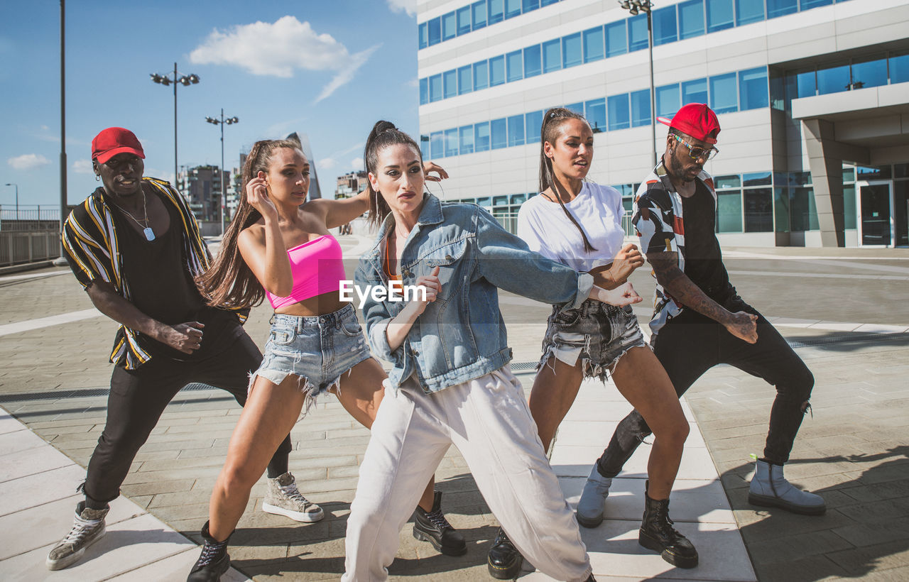 Friends dancing against building in city