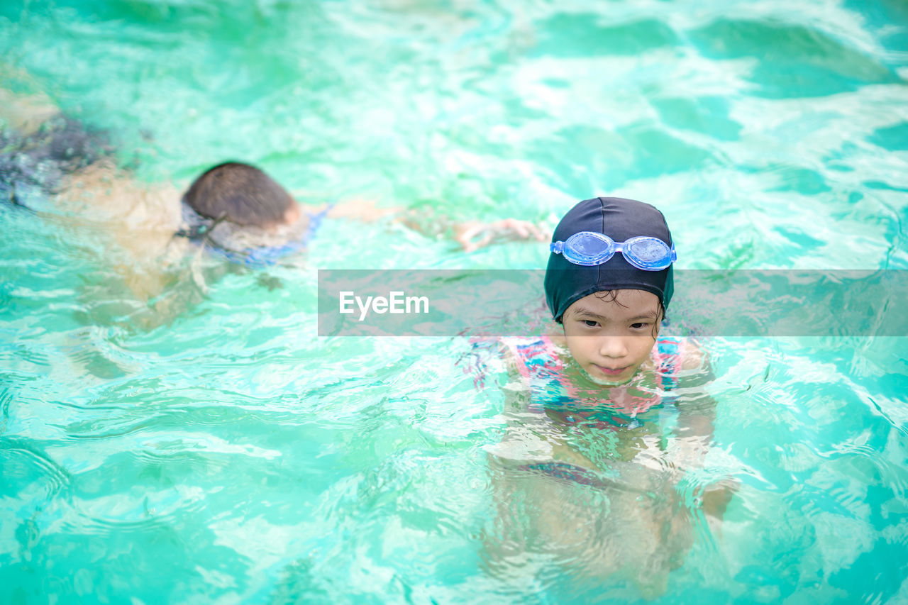 High angle view of girl and boy swimming in pool 