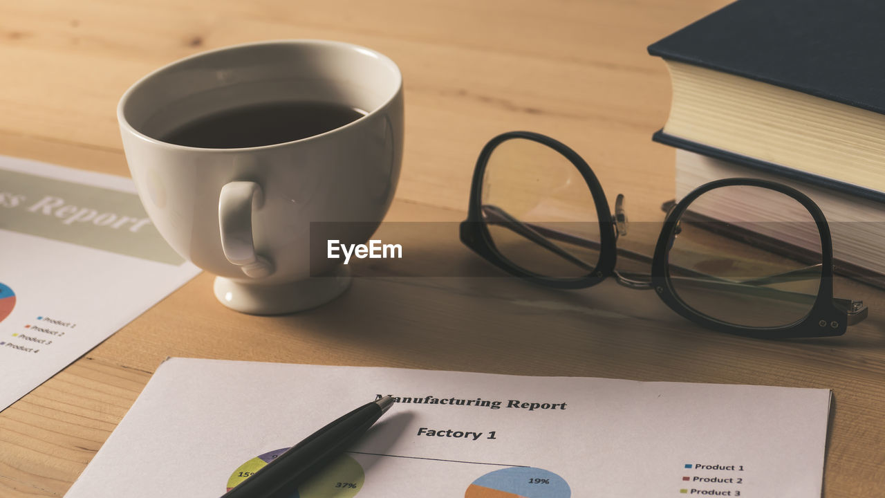 CLOSE-UP OF COFFEE CUP WITH BOOK AND SPOON ON TABLE