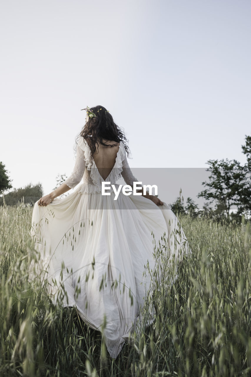 Bride walking in the countryside in a long wedding dress.