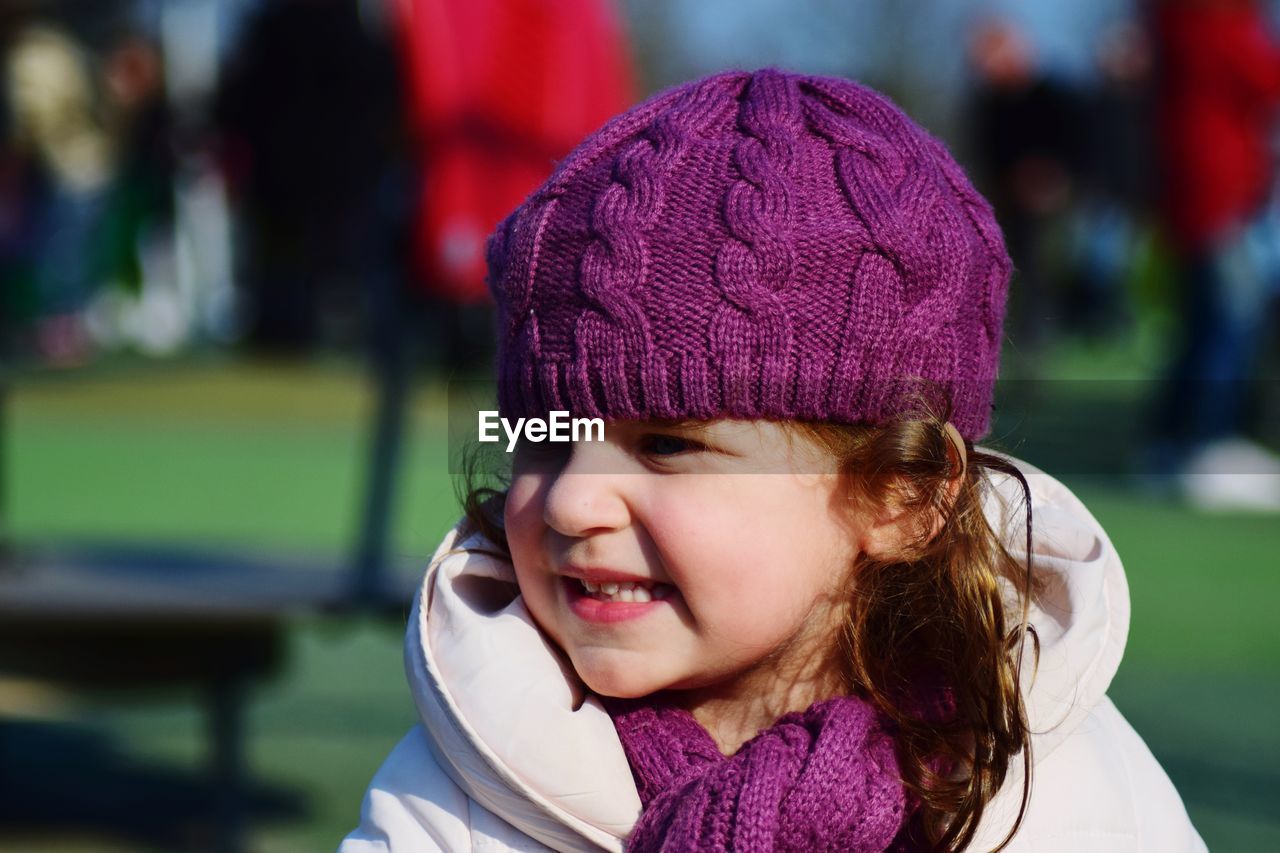 Close-up of smiling girl wearing purple knit hat outdoors