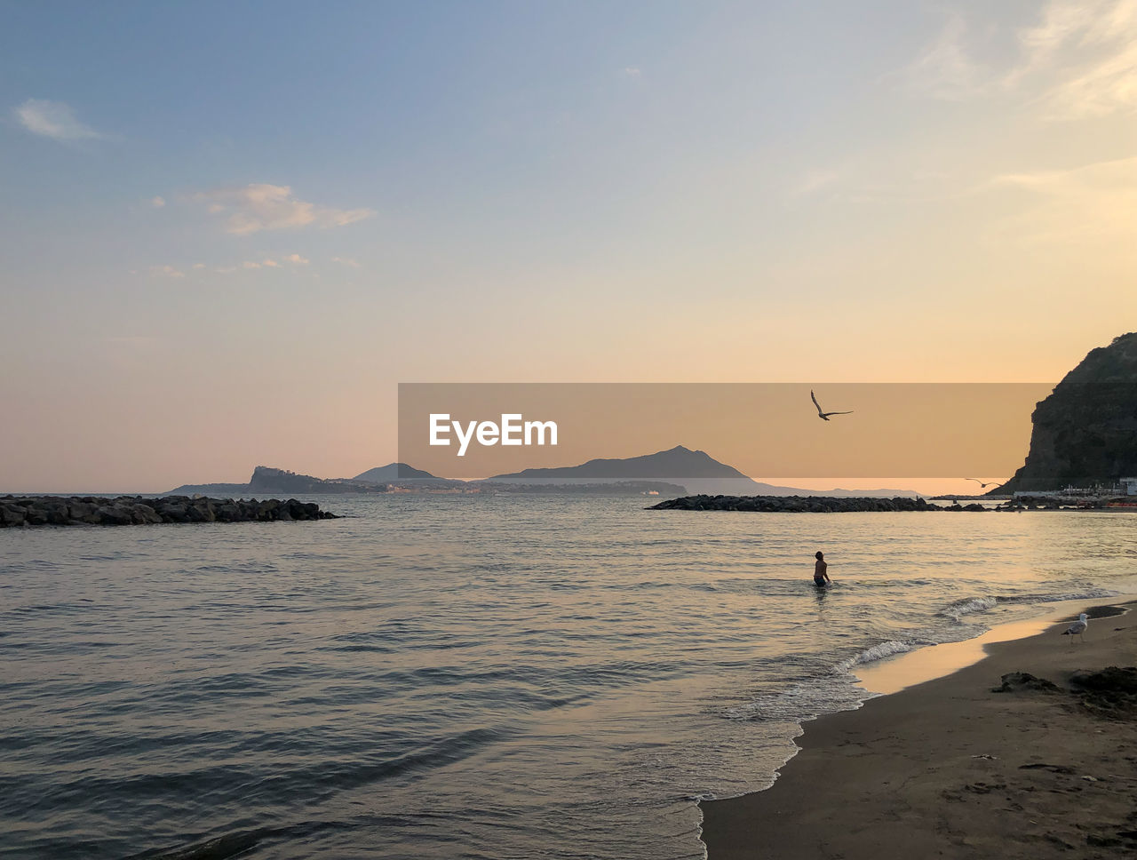 SCENIC VIEW OF BEACH AGAINST SKY DURING SUNSET