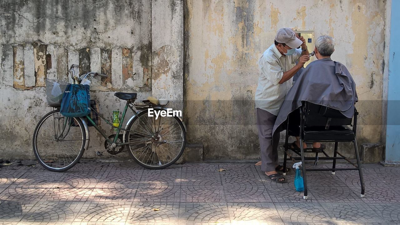 REAR VIEW OF MAN WITH BICYCLE STANDING ON FLOOR