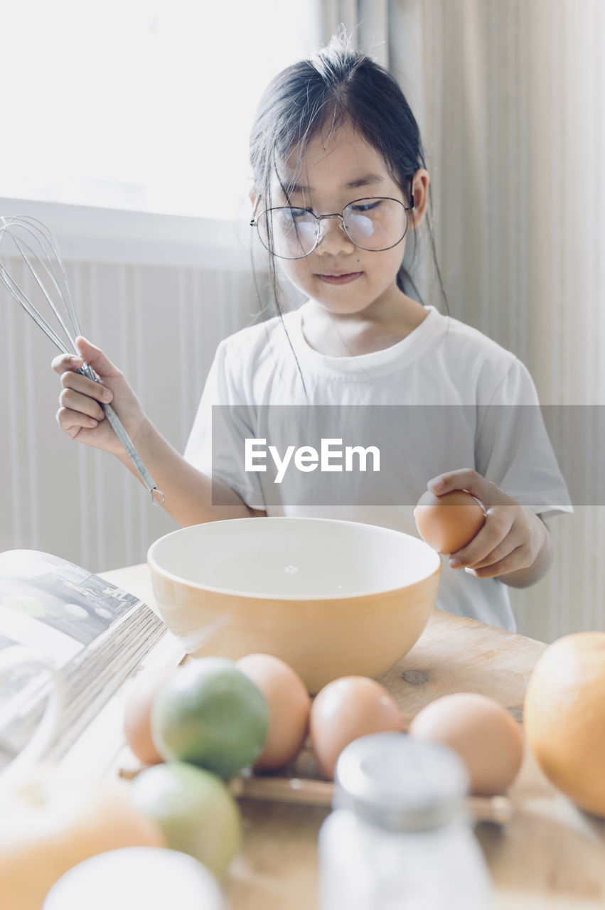 Girl preparing food while standing in kitchen at home