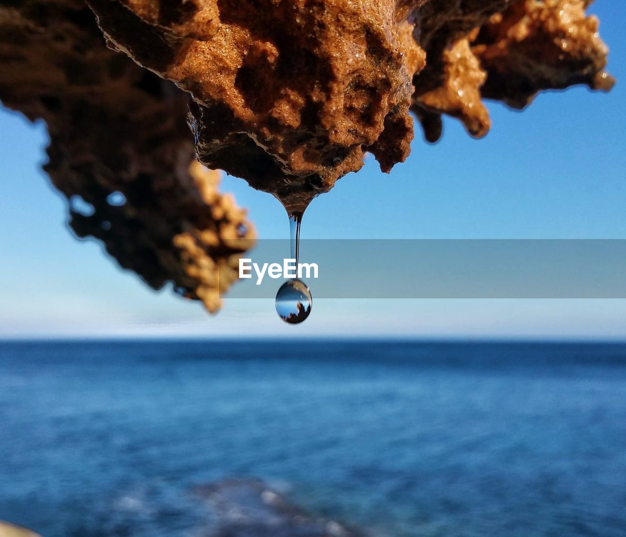 CLOSE-UP OF WATER DROP ON SEA AGAINST CLEAR SKY