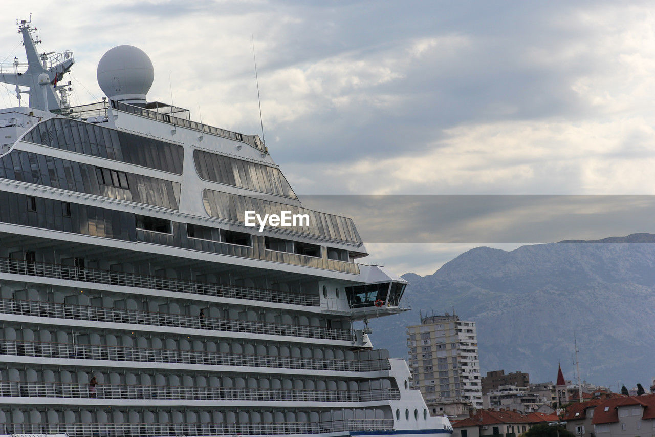 cruise ship, passenger ship, architecture, ship, built structure, vehicle, building exterior, watercraft, sky, nature, sea, building, travel, ocean liner, boat, city, travel destinations, cloud, tourism, business finance and industry, transportation, water, tourist, nautical vessel, industry, construction industry, outdoors, business, naval architecture, environment, tower, mountain, motor ship