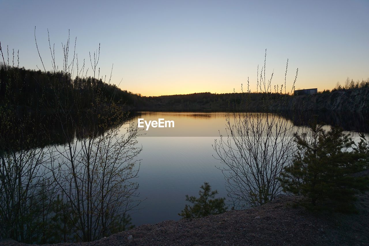 SCENIC VIEW OF LAKE AGAINST CLEAR SKY AT SUNSET