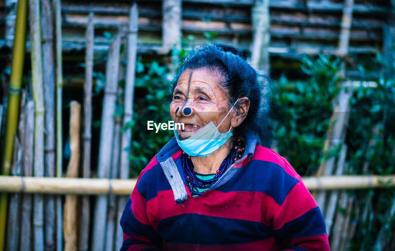 Senior woman wearing mask looking away while standing outdoors