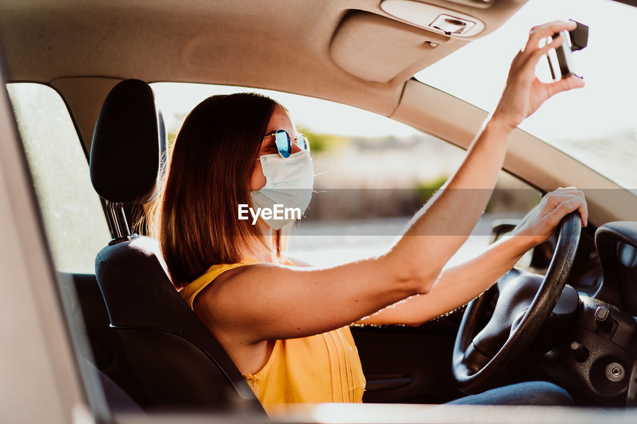 Portrait of young woman using phone while sitting in car