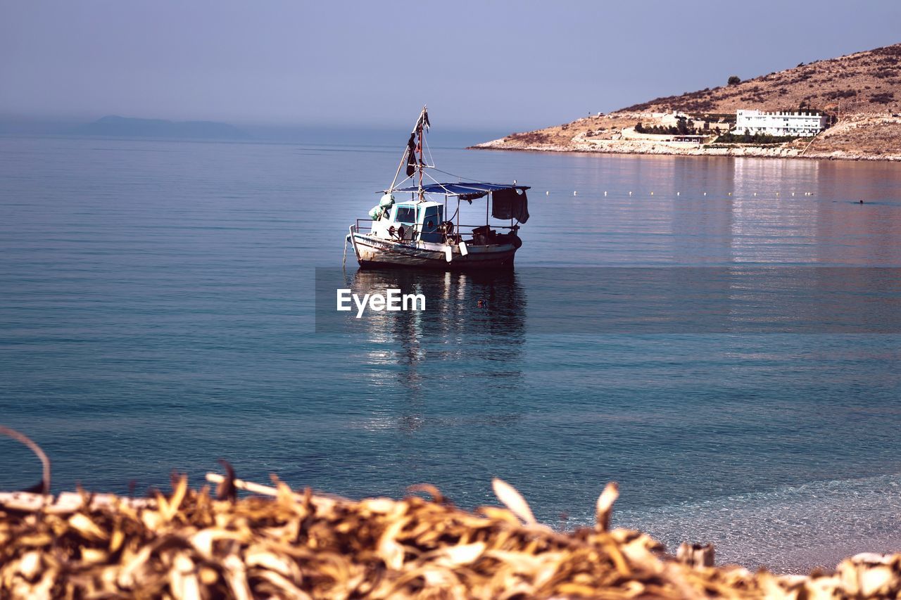 SAILBOATS MOORED IN SEA AGAINST CLEAR SKY