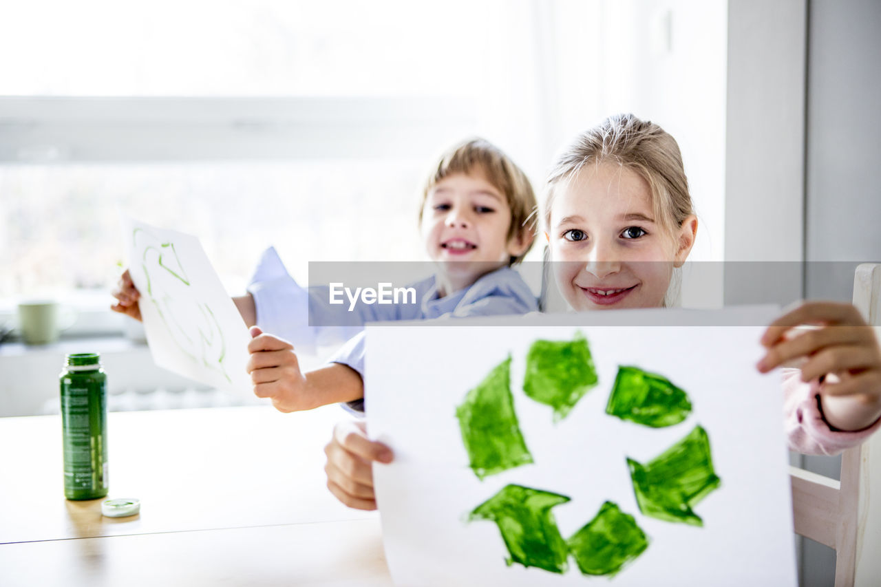 Girl holding paper with painted recycling symbol
