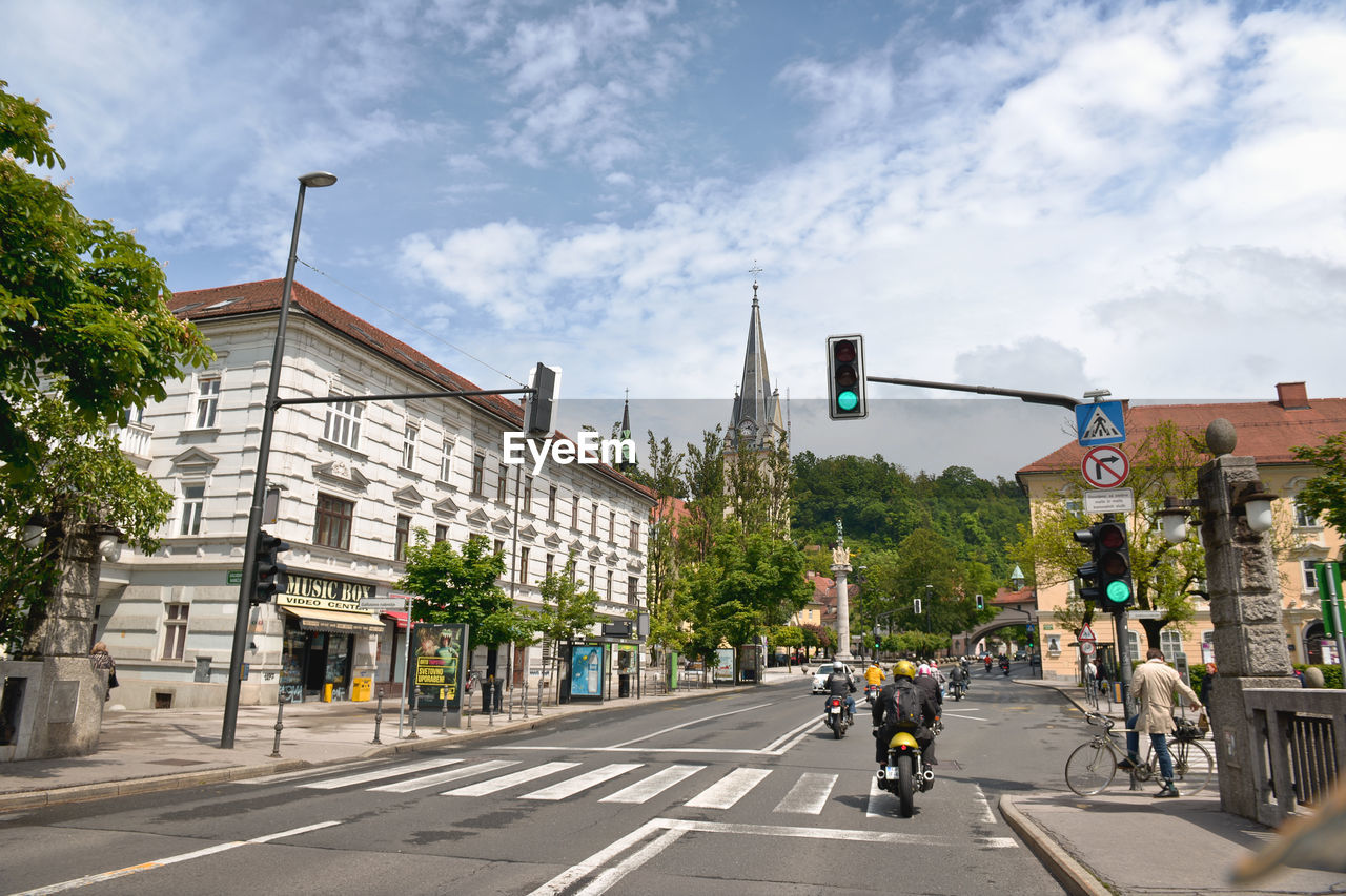 Road by buildings in city against sky