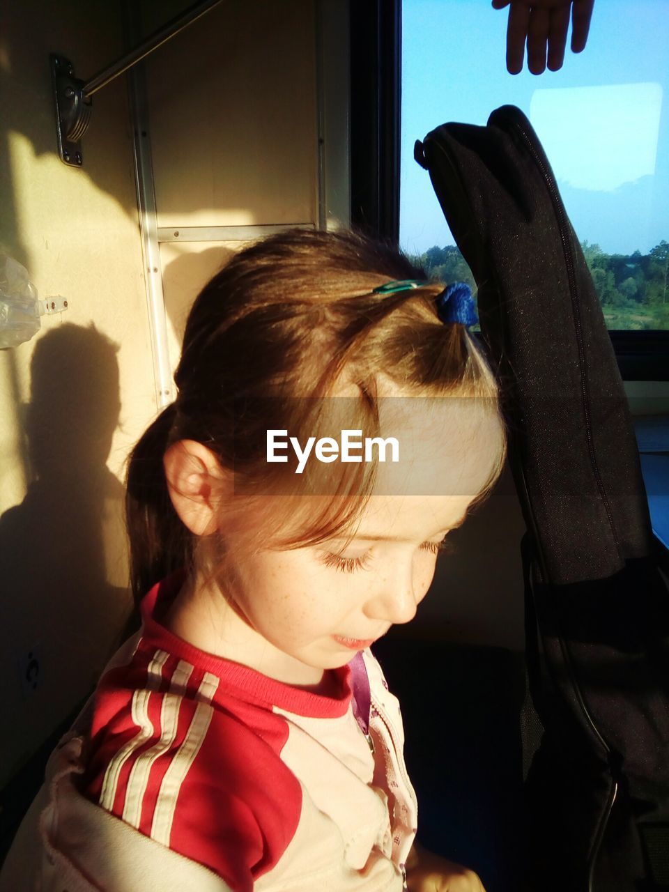 Close-up of girl standing by guitar case in train