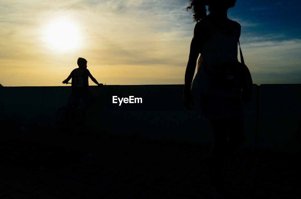 SILHOUETTE PEOPLE STANDING ON BEACH DURING SUNSET