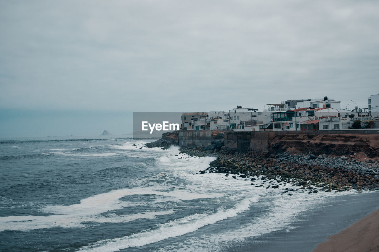 Buildings by sea against sky