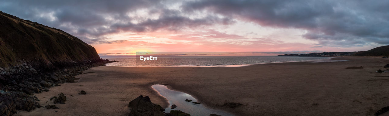 SCENIC VIEW OF BEACH AGAINST SKY AT SUNSET