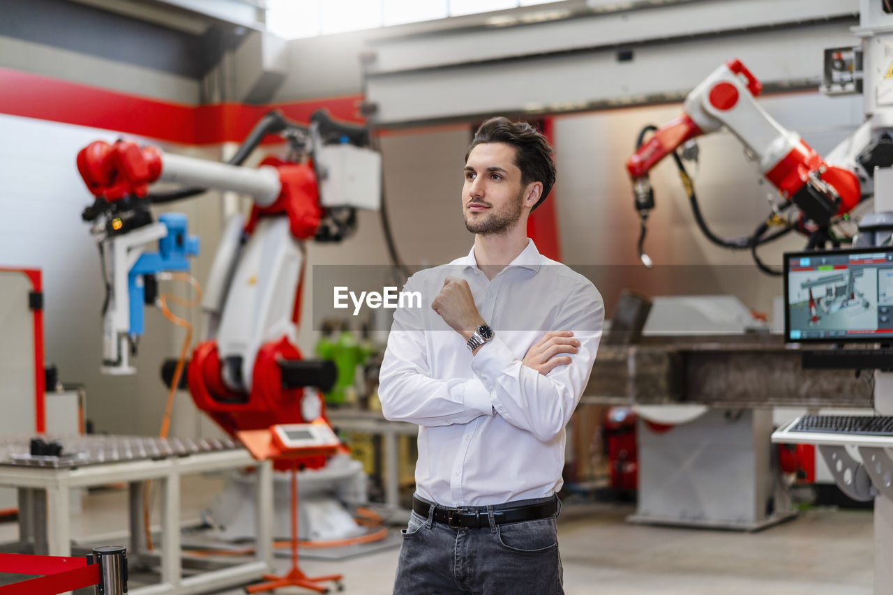 Thoughtful engineer standing in robot factory