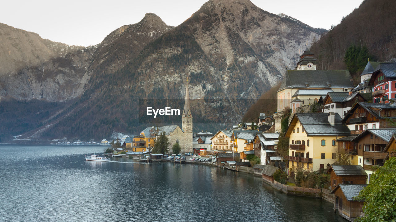 Town by lake and mountains against sky