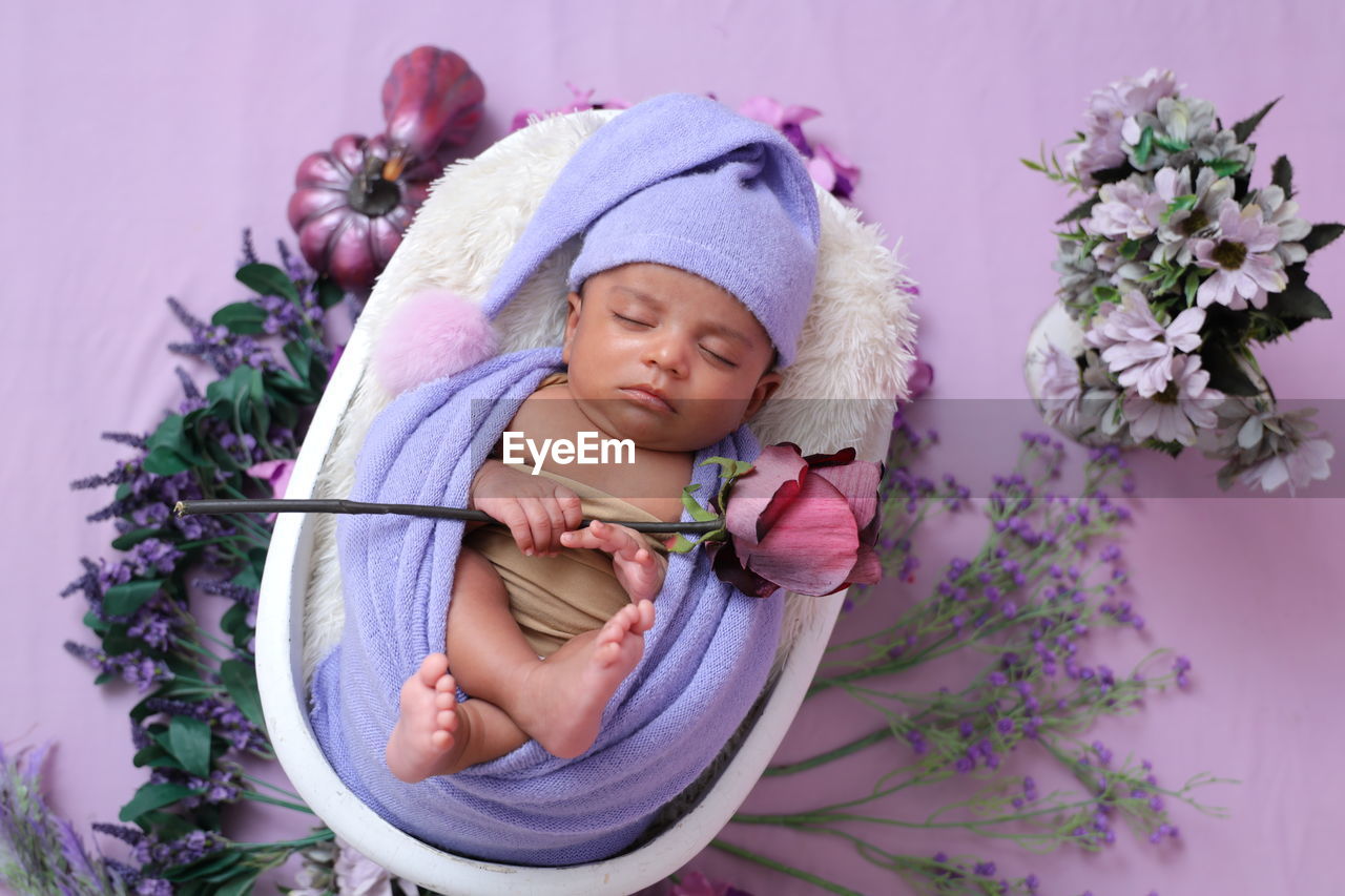 Baby boy with lavender swaddle blanket and a rose