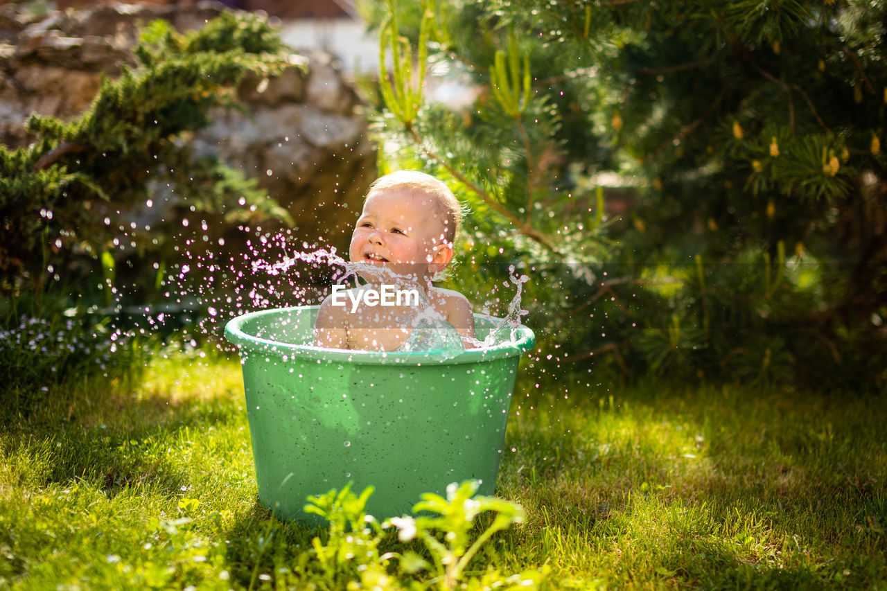 Cute baby girl playing in bucket at lawn