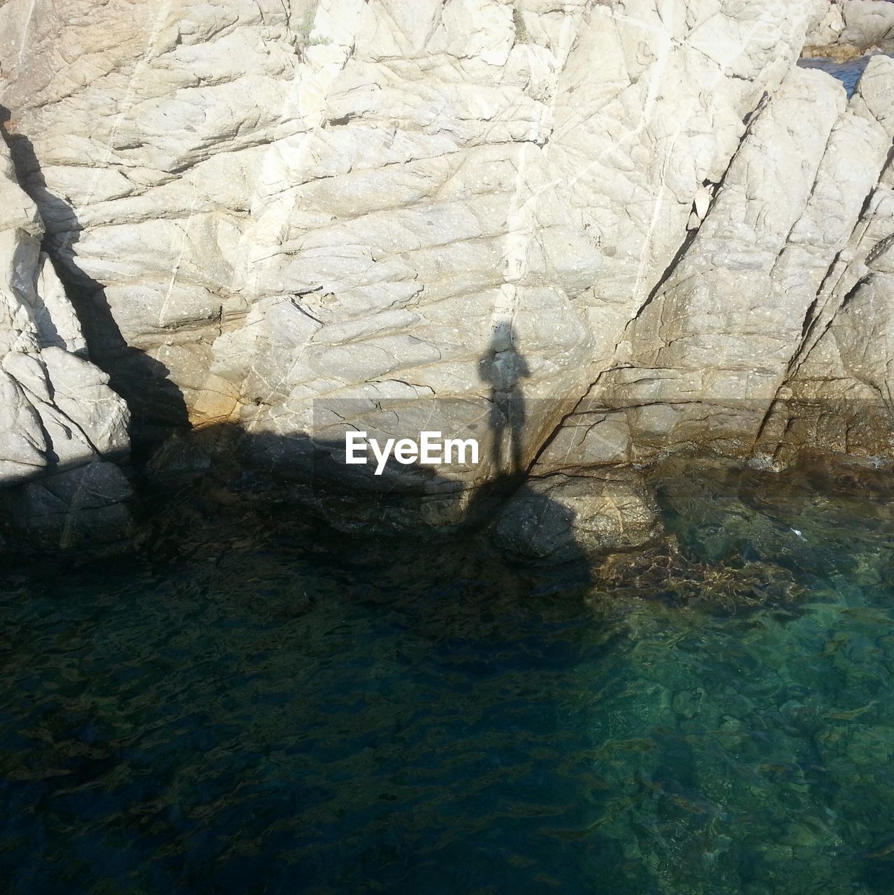 Shadow of person on rocks at coast