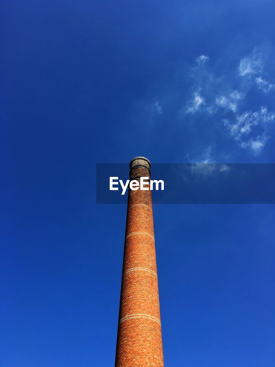 Low angle view of a brick chimney against blue sky